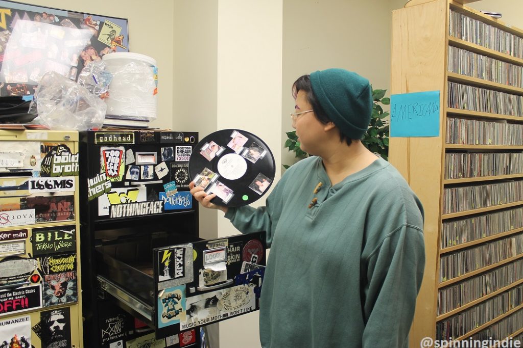 Sidney Yi showing up decorated LP. CD library in the background. Photo: J. Waits