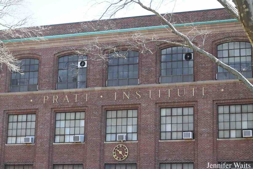 Photo of building at Pratt Institute. "Pratt Institute" is written in metal letters on an old building with many multi-paned windows. March, 2023 photo by J. Waits.
