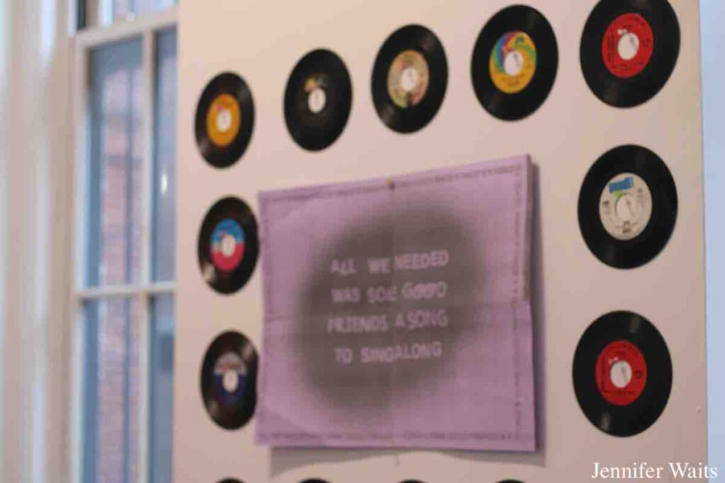 Vinyl decor on the wall of college radio station WPIR Pratt Radio in March, 2023. 7" records surround a purple poster that reads: "all we needed was some good friends a song to sing along." Photo: J. Waits