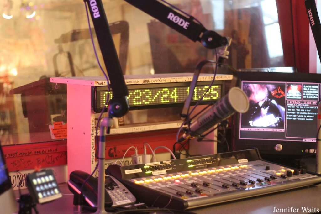 Equipment in WBOR studio at Bowdoin College. Pictured: computer monitor, microphone, mixing board, telephone, LED sign with date and time. Photo: J. Waits