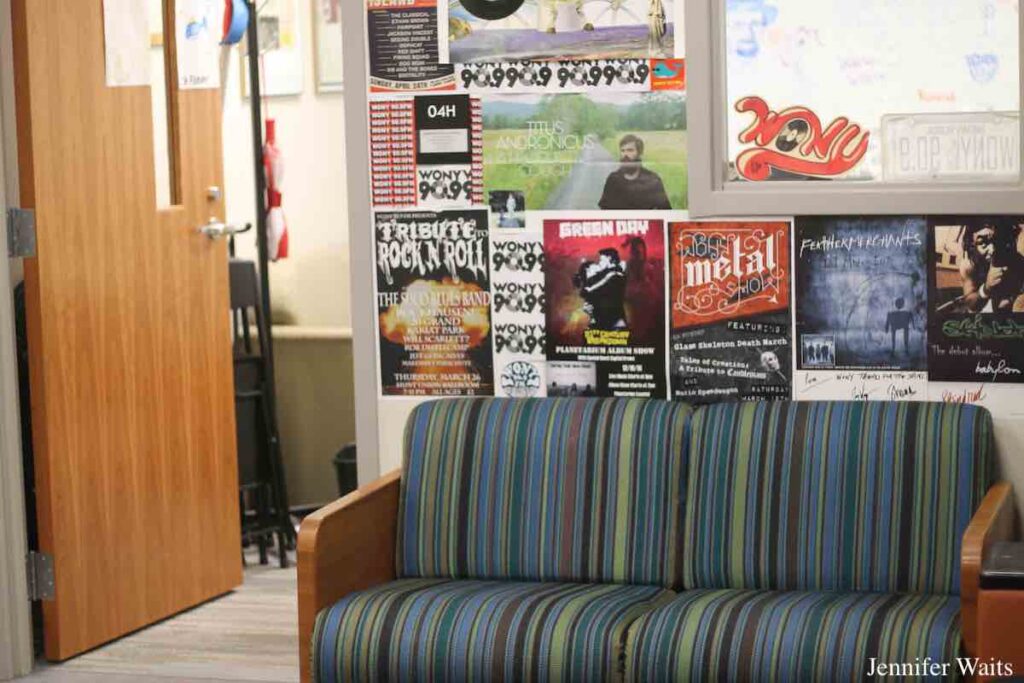 Photo of lobby at college radio station WONY-FM. Pictured is a green and blue striped couch with posters hanging on a wall above it. Photo: J. Waits