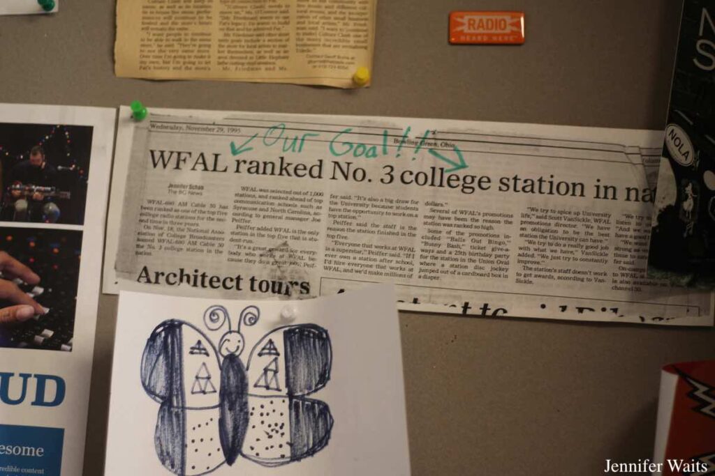 Photo of bulletin board at college radio station WBGU-FM. On the board is a newspaper clipping with the headline "WFAL ranked no. 3 college station..." A handwritten note about the headline says "Our Goal!" Photo: J. Waits