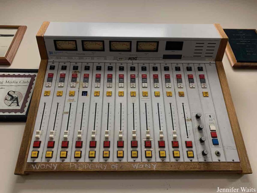 Photo of radio station console hanging on the wall at WONY-FM. Next to it are framed certificates and an award plaque. Photo: J. Waits