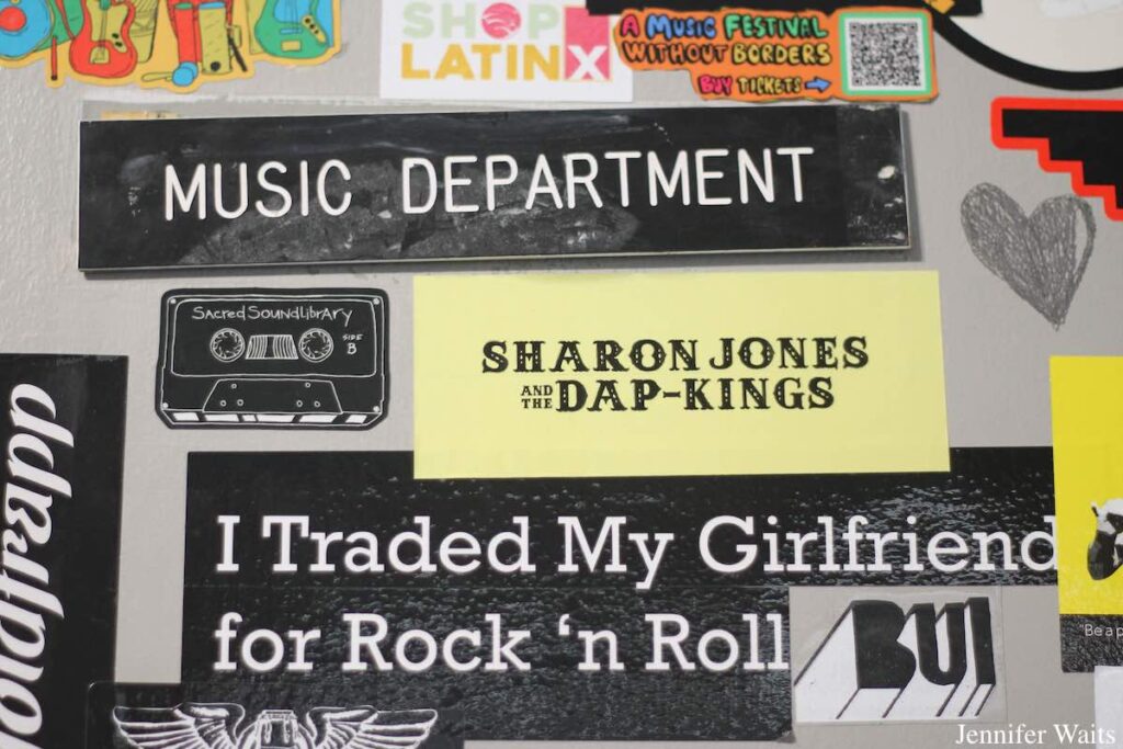 Photo of Music Department office door at college radio station KUCR. A sign on the door reads "Music Department" and there are stickers all over the door, including one for Sharon Jones and the Dap-Kings. Photo: J. Waits