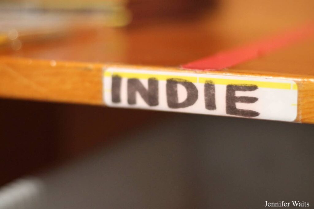 Photo of shelf at college radio station KUCR. Wooden shelf is labeled with a sticker that reads 'INDIE." Photo: J. Waits