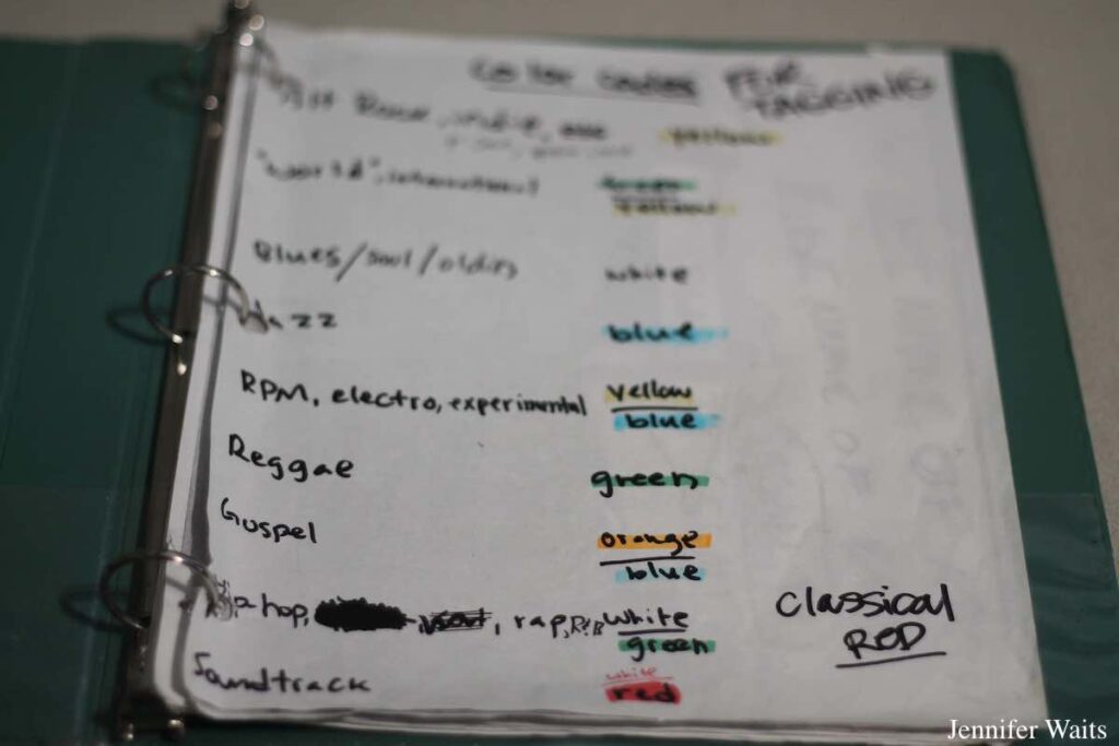 Photograph of green binder open to a page with description of color codes for music genres in the library of college radio station KUCR. Photo: J. Waits